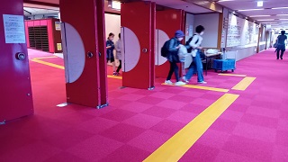 茨城県武道館の会場内に仮設設置したイエローの誘導マットを頼りに移動する視覚障害の選手たち