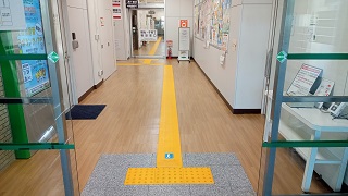 松山市役所別館内の既存点字ブロックから延びるイエローの誘導マット