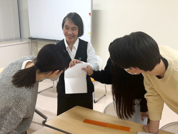 点字用紙の説明をする亀山様と、実際に触って印字を確かめるインタビュアー。