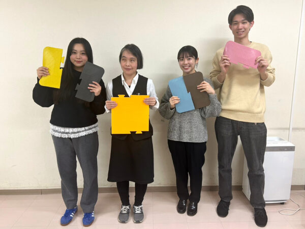 亀山様インタビュー後の記念撮影。インタビュアーの３人と、インタビュイーの亀山様が4人で並び、それぞれ誘導マットを体の前で持っている。